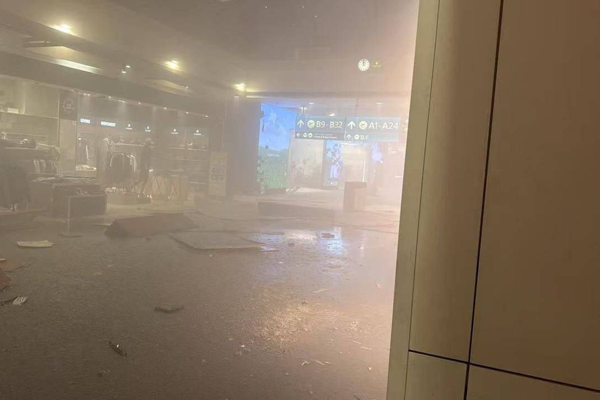 Interior view of a smoke-filled room with an illuminated screen, partially obscured by smoke and featuring blurred furnishings and ambient lighting.