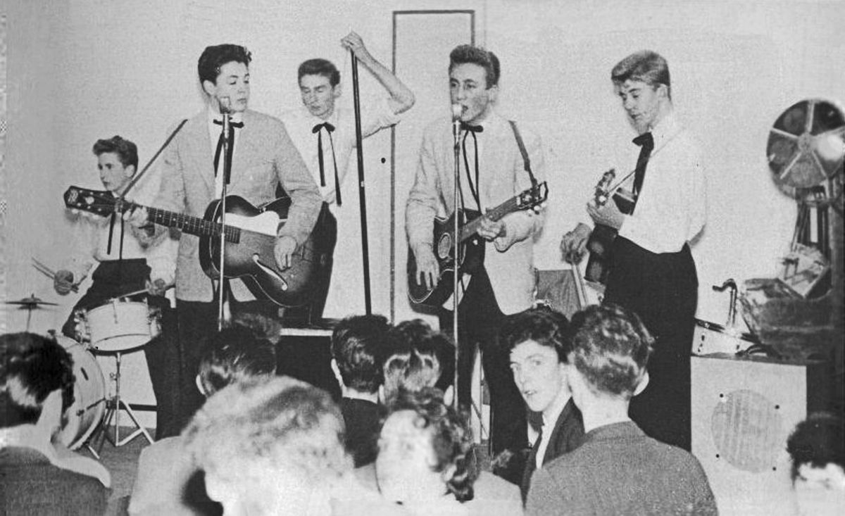 The earliest known photograph of John and Paul performing together, as part of The Quarrymen in the autumn of 1957 at Wilson Hall (opposite Garston Bus Depot), Speke Road, Garston. Left to right: Colin Hanton (drums), Paul McCartney (guitar & vocals), Len Garry (tea chest bass), John Lennon (guitar & vocals), Eric Griffiths (guitar).
