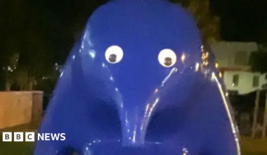 Large blue animal sculpture with a long nose and two googly eyes