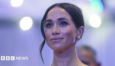 A close up of a woman with dark hair in an up-do and silver earrings