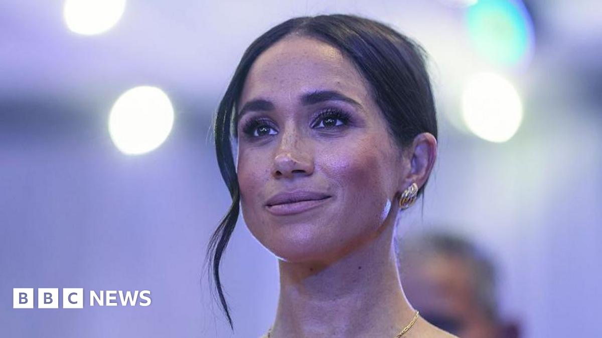 A close up of a woman with dark hair in an up-do and silver earrings