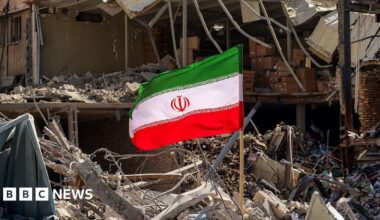 An Iranian flag is placed amid rubble and debris next to a destroyed residential building near Ferdowsi square in Tehran on March 3, 2026.