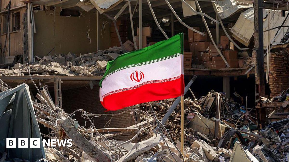 An Iranian flag is placed amid rubble and debris next to a destroyed residential building near Ferdowsi square in Tehran on March 3, 2026.