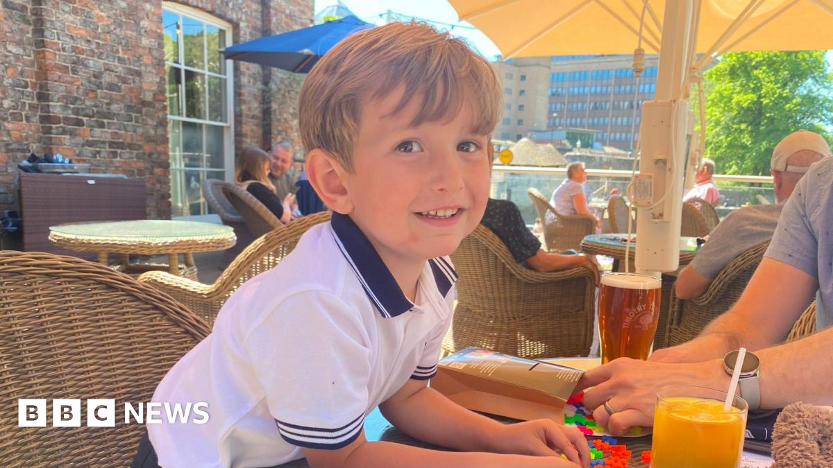 Angel Godoy's wife hold up an orange T-short with writing on it, a message her husband scrawled on it while he was in prison in Venezuela