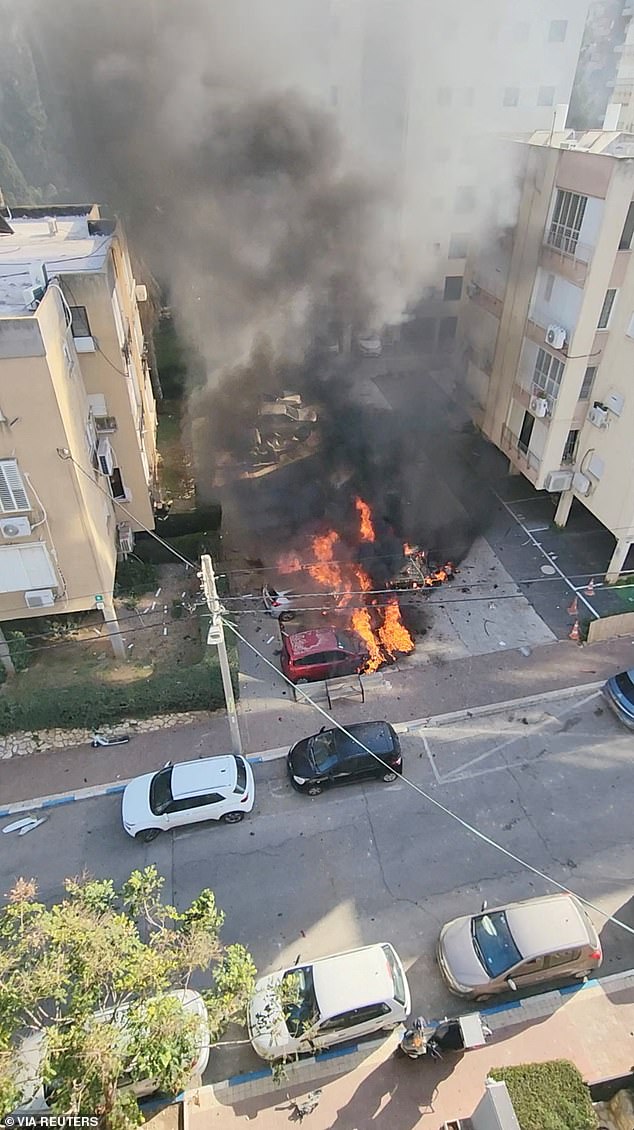 Smoke and flames rise from vehicles after shrapnel from an Iranian missile strike fell on a parking lot, in Ramat Gan, Israel