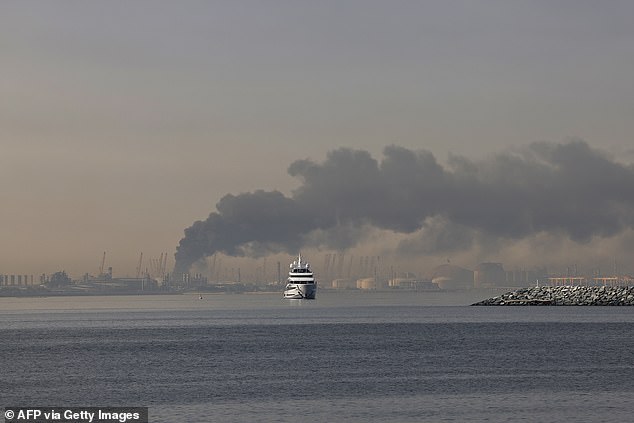 A yacht sails past a plume of smoke rising from the port of Jebel Ali following an Iranian strike in Dubai on March 1