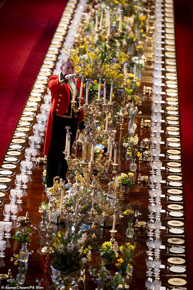 A member of Royal Household wears shoe coverings while standing on the banquet table in order to light candles