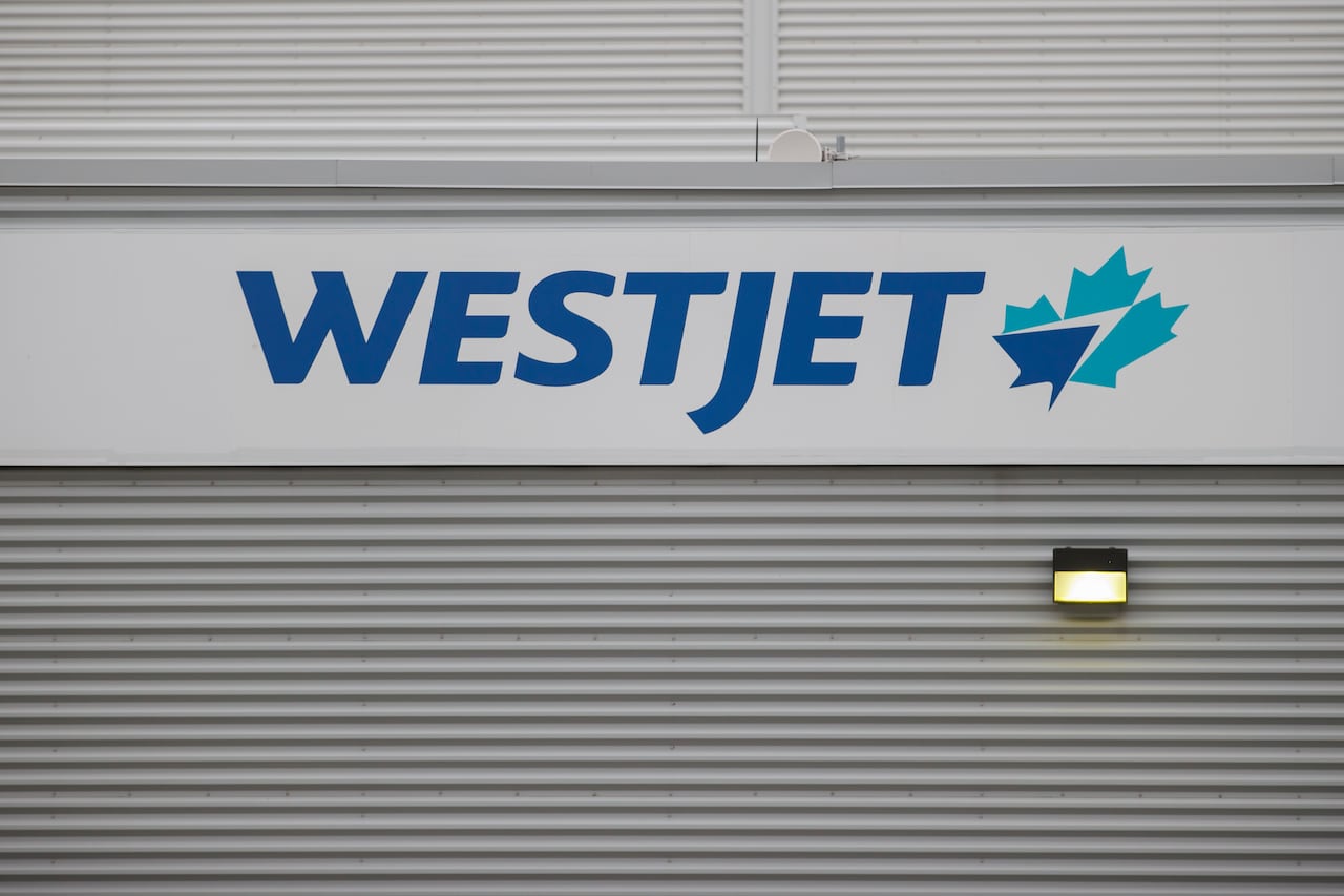 The logo of the WestJet airline, appearing on the side of an airport hangar