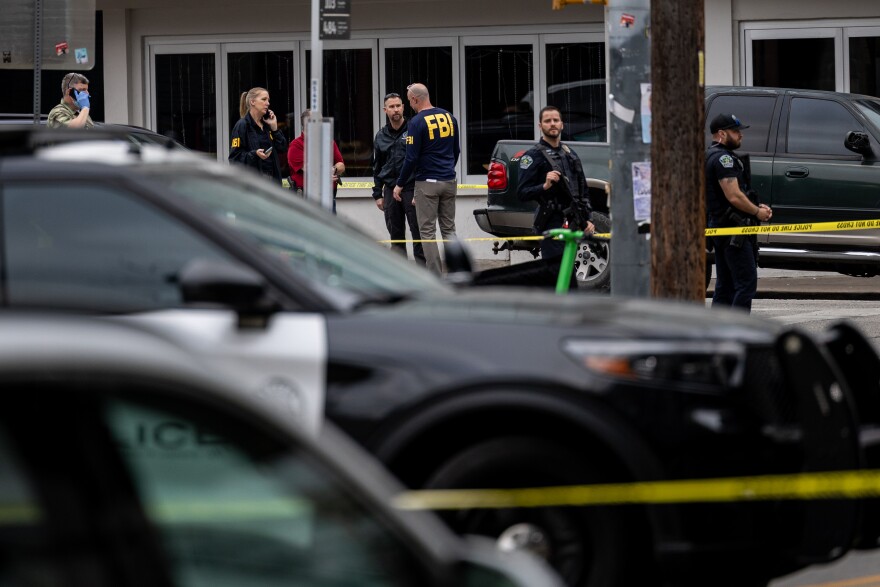 Members of the Austin Police Department and FBI are seen outside a building talking.