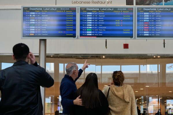 Travelers check departure times as many flights are cancelled at Beirut Rafik Hariri International Airport in Beirut, Lebanon, Saturday, Feb. 28, 2026, as many airlines canceled flights due to the conflict involving the United States, Israel and Iran. (AP Photo/Hassan Ammar)
