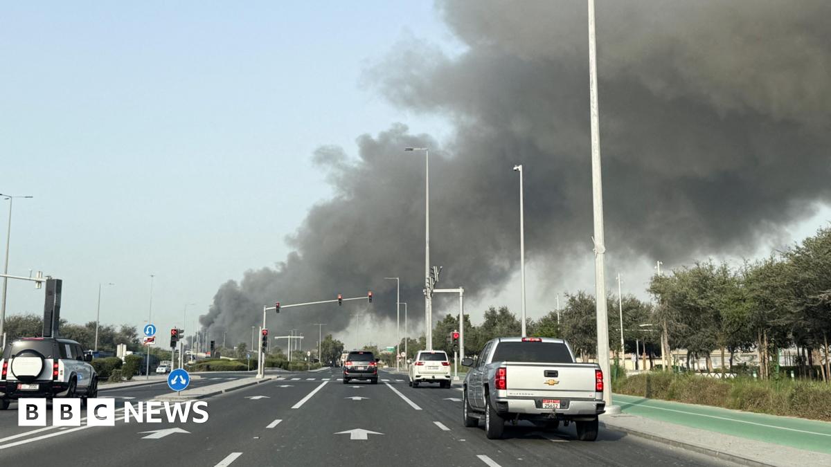 Several vehicles are seen on a multi-lane road in Abu Dhabi as smoke billows from Zayed port in the distance in the left of the picture