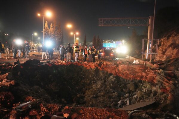 Israeli security forces inspect a damaged road after a missile launched from Iran struck Jerusalem, Sunday, March 1, 2026.(AP Photo/Mahmoud Illean)