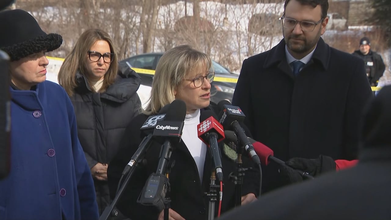 Coun Rachel Chernos Lin is surrounded by people in winter clothes and reporters microphones outside a synagogue taped off by police tape