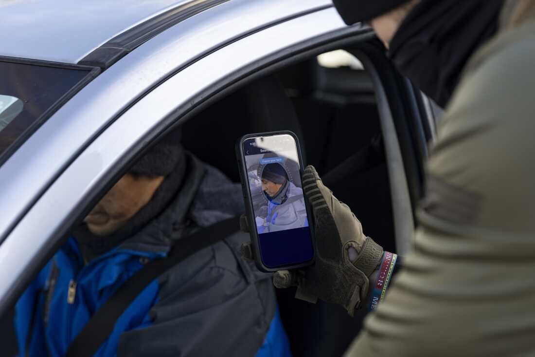 Border Patrol Agent scans the face of a driver as they stop and question him in the street during an Immigration Enforcement Operation in Minneapolis on Jan. 13.