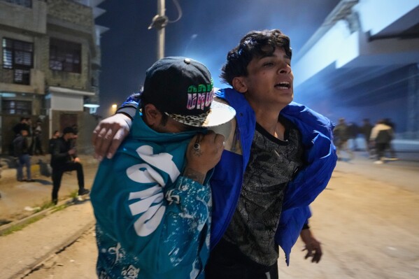 Protesters react to tear gas fired by Riot police during to disperse a protest against U.S. and Israeli attacks on Iran, at a bridge leading to the fortified Green Zone where the U.S. Embassy is located, in Baghdad, Iraq, Monday, March 2, 2026. (AP Photo/Hadi Mizban)