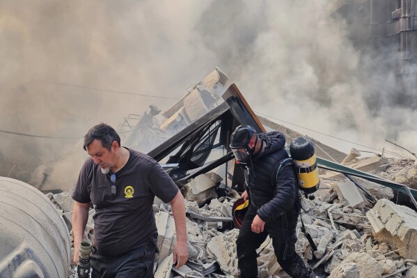 Firefighters inspect the rubble as smoke rises from a building hit by an Israeli airstrike in Dahiyeh, a southern suburb of Beirut, Lebanon, Tuesday, March 3, 2026. (AP Photo/Hassan Ammar)