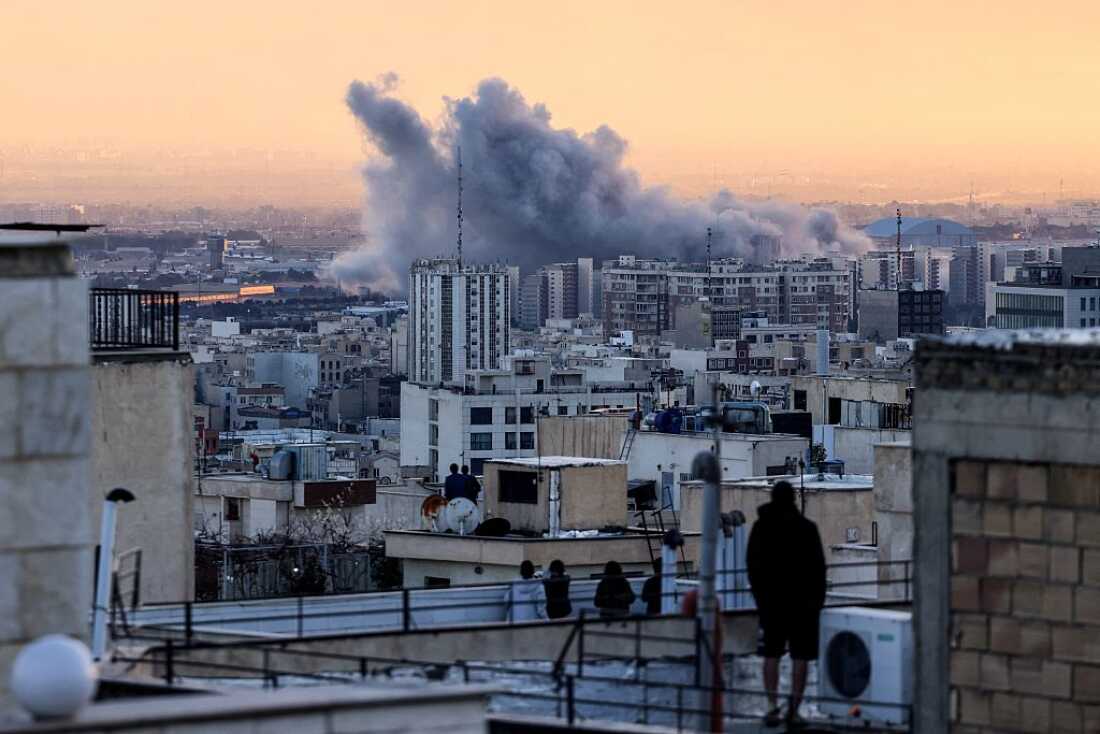 A person stands on the roof of a building looking at a plume of smoke rising after a strike on the Iranian capital Tehran, on Tuesday.