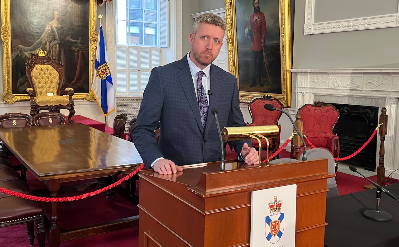 A man in a suit and tie stands behind a podium.