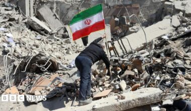 A man plants the Iranian flag on a pile of rubble in Tehran.