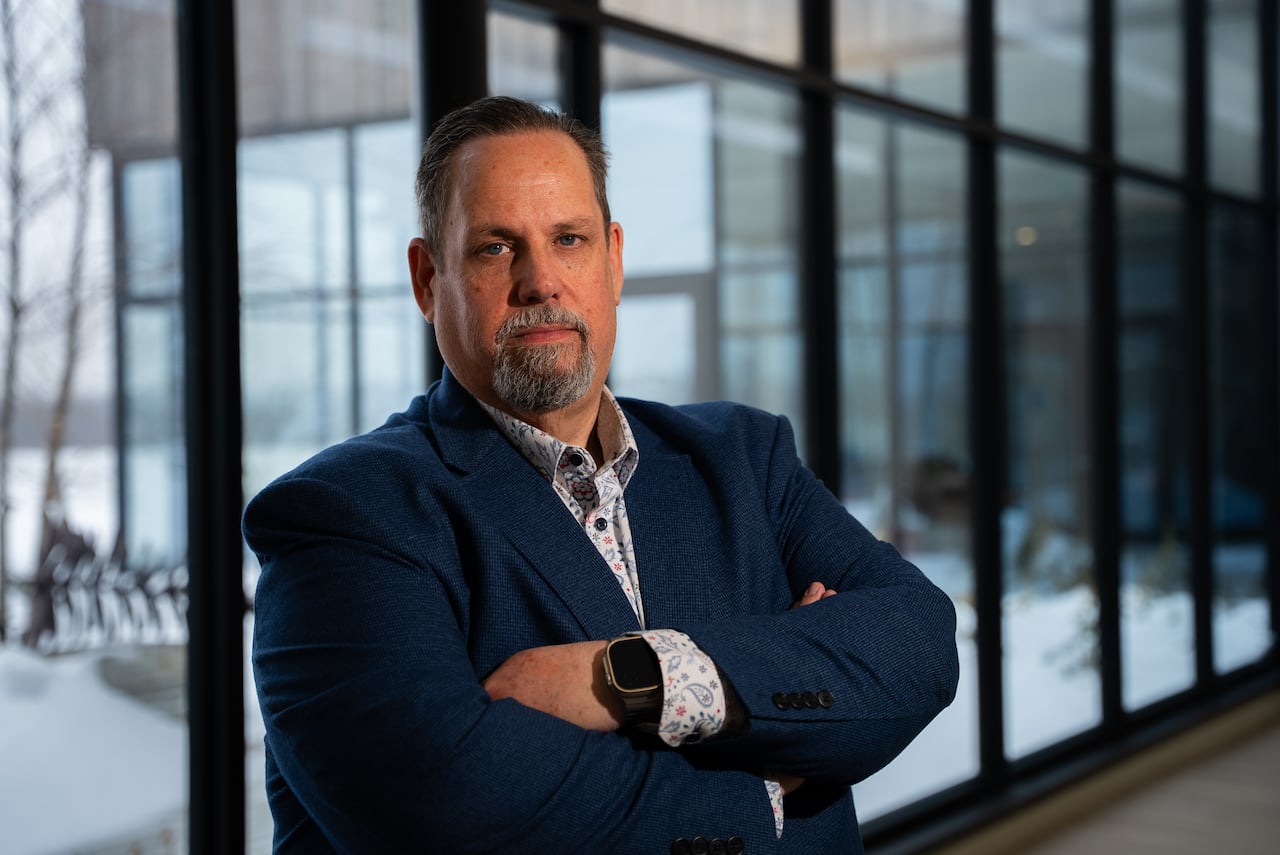A man in a suit stands with his arms crossed
