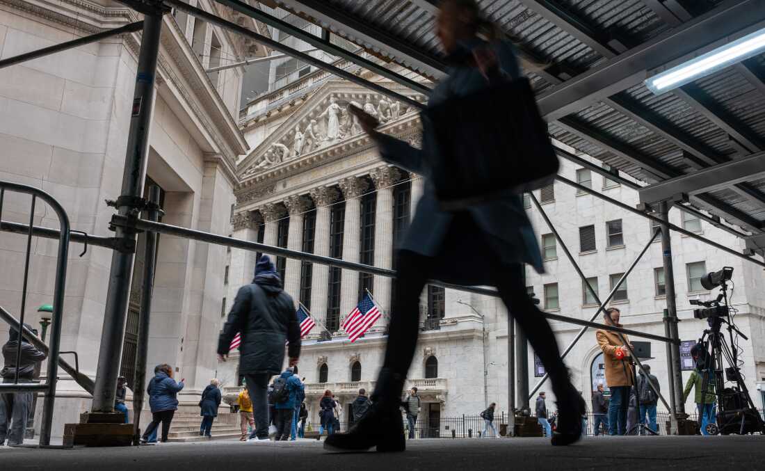 People walk by the New York Stock Exchange on Wall Street.