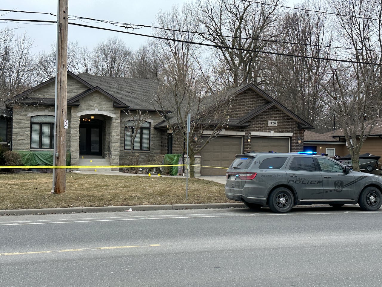 A home surrounded by police tape, with a LaSalle police cruiser parked in front.