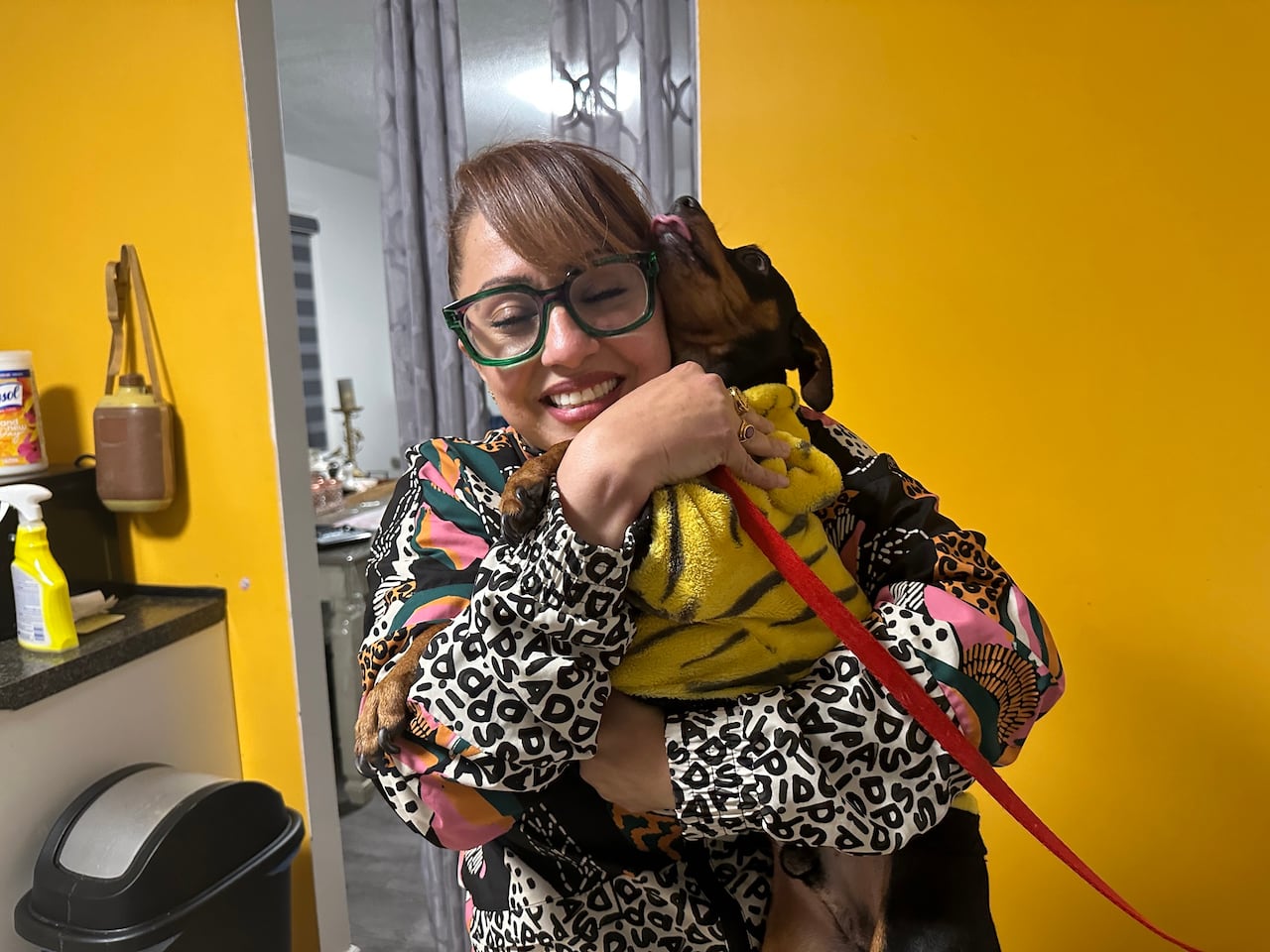 Woman in her kitchen hugging a small black dog