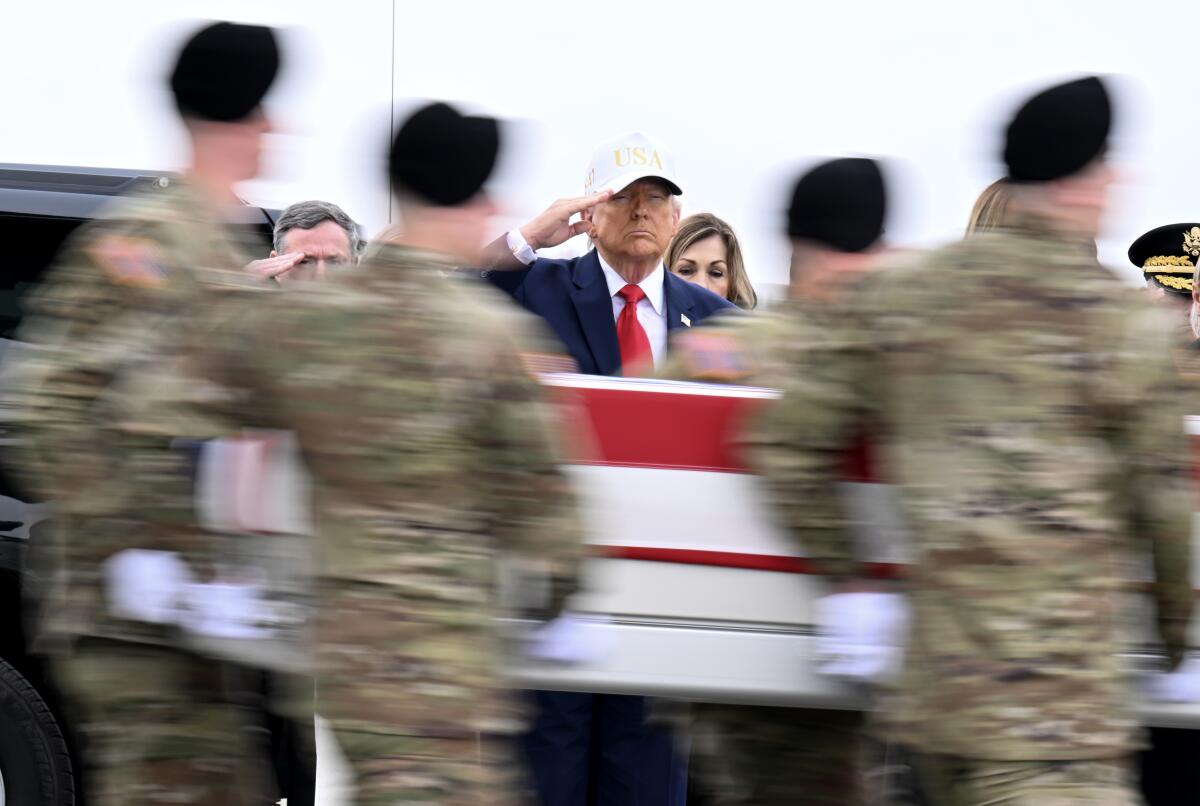 President Trump salutes as soldiers carry a flag-draped coffin