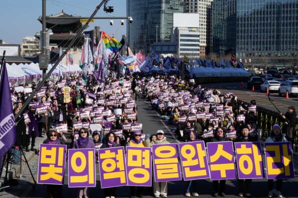 South Korean activists gather a day ahead of International Women's Day in Seoul, South Korea, Saturday, March 7, 2026. The banners read "Complete the revolution of light." (AP Photo/Ahn Young-joon)