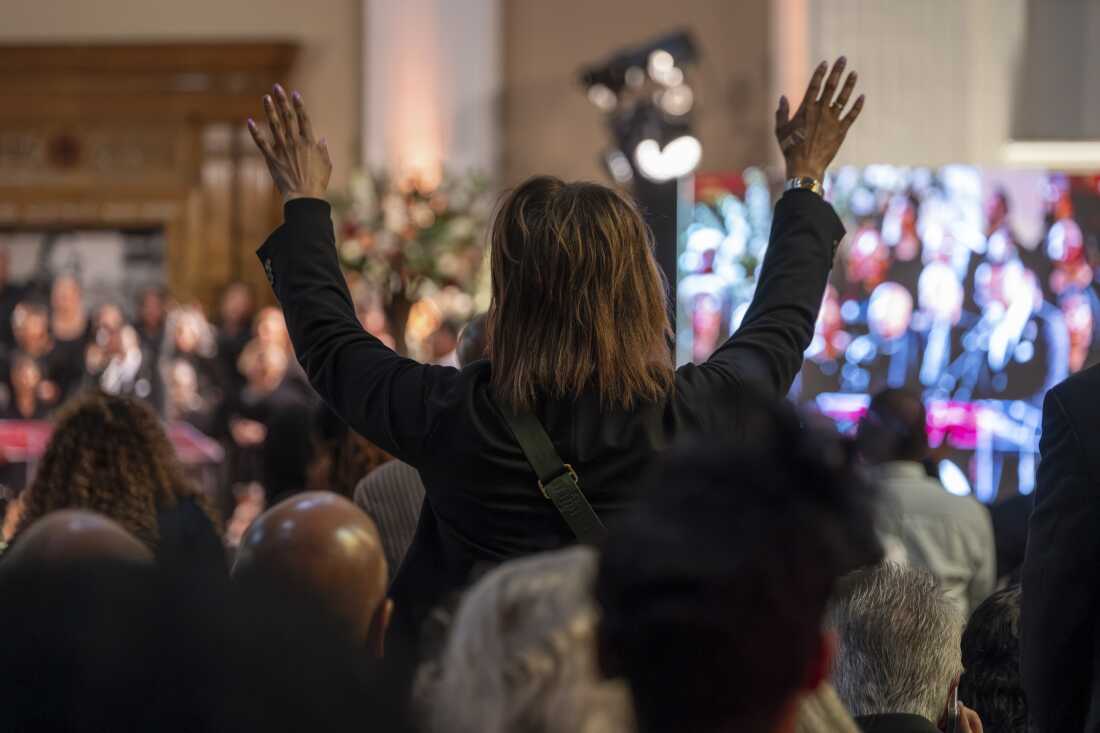 A supporter raises their hands during the funeral service for the Rev. Jesse Jackson at the headquarters of the Rainbow PUSH Coalition. (Kenn Cook Jr. for NPR)