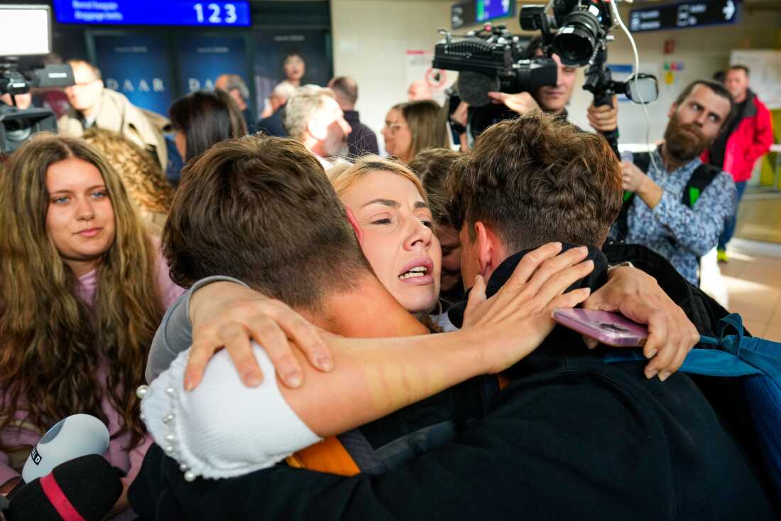 A family hugs after disembarking from an evacuation flight on a commercial airplane from Muscat, Oman, at the Henri Coanda International Airport in Otopeni, Romania.