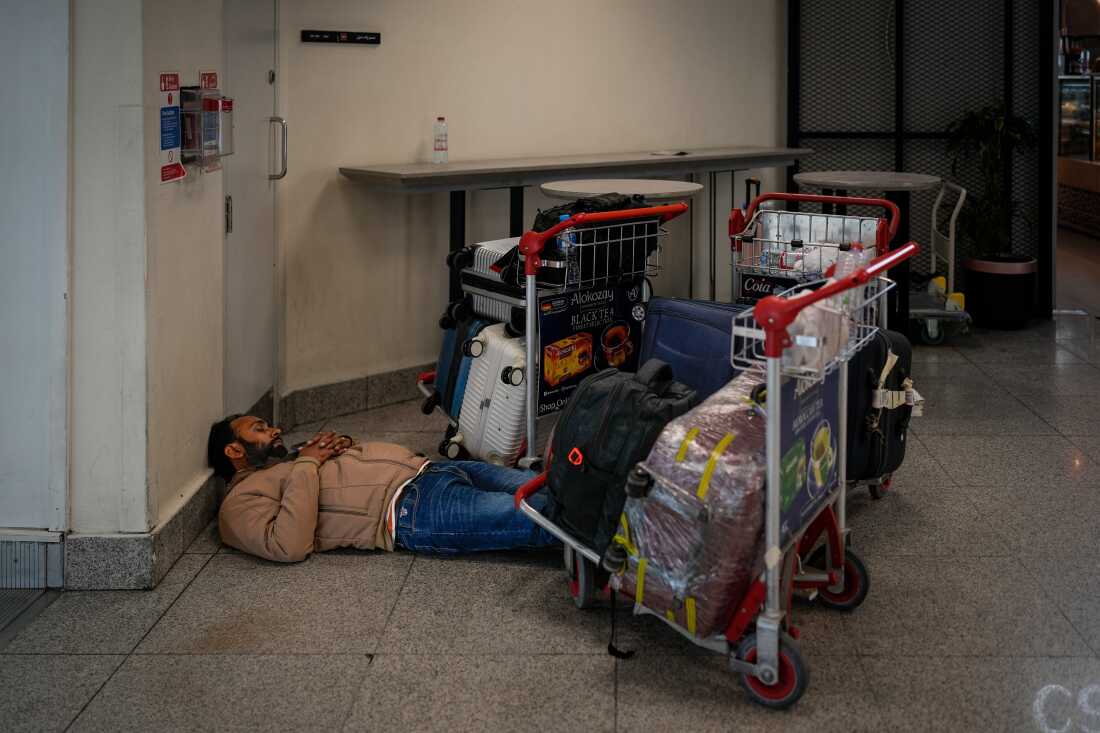 A stranded passenger sleeps on the floor outside Dubai International Airport terminal as the airport resumes limited operations in Dubai, United Arab Emirates.