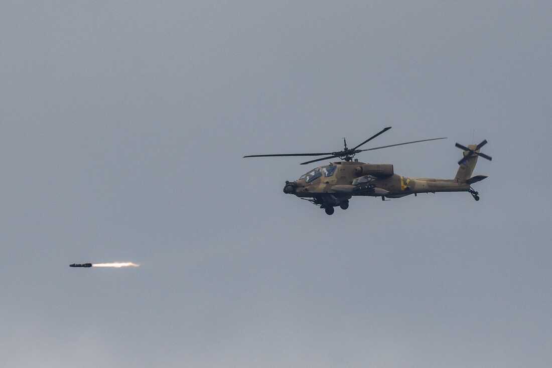 An Israeli Air Force AH-64 Apache attack helicopter fires rockets while flying at a position along the border between northern Israel and southern Lebanon.