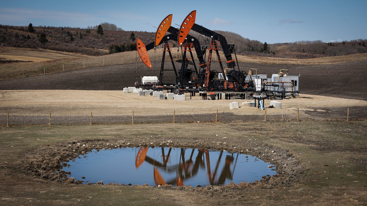 A pump jack machine sits on a field.