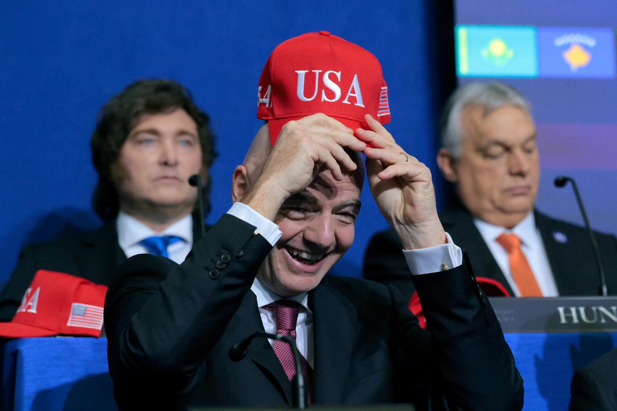 FIFA president Gianni Infantino holds up a USA hat as he attends the inaugural meeting for the Board of Peace.
