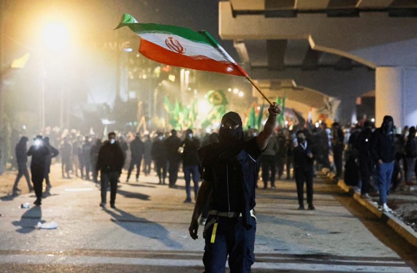 A PROTESTER holds an Iranian flag as supporters of Iraqi Shi'ite armed groups attempt to move toward the US embassy located in Baghdad's Green Zone, while riot police deploy to block their advance, following the Israel and US strikes on Iran and the killing of Iran’s Supreme Leader, in Baghdad.