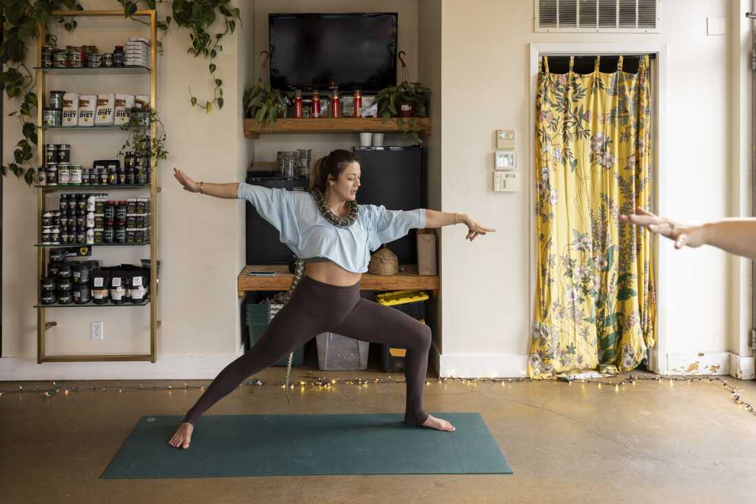 Snake Yoga instructor Katy Vanek brings the class into Warrior II pose with Gemma, a carpet python, wrapped around her neck.