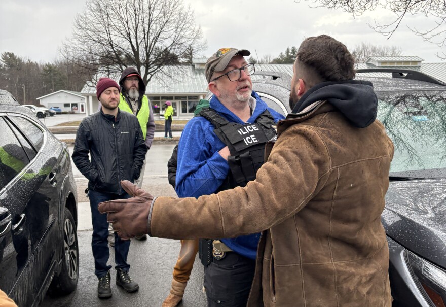 A person stands close to a law enforcement officer who wears a vest reading "Police ICE"