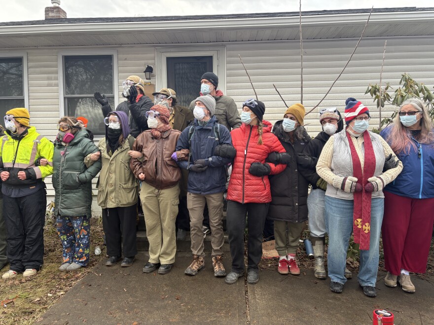 People link arms in front of a house