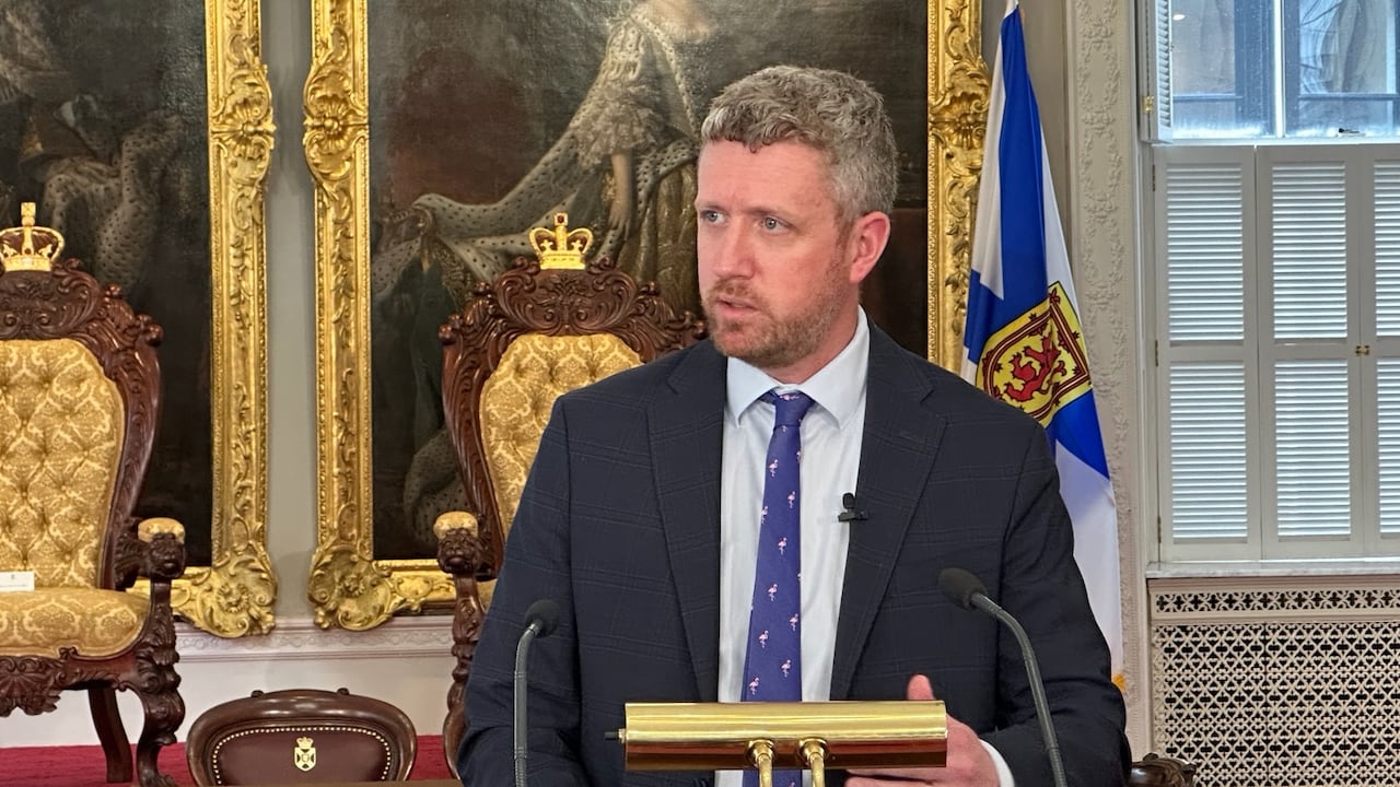 A man in a suit and tie stands behind a podium.