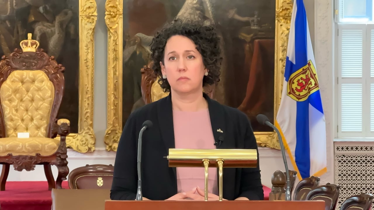 A woman in a black jacket stands behind a podium.