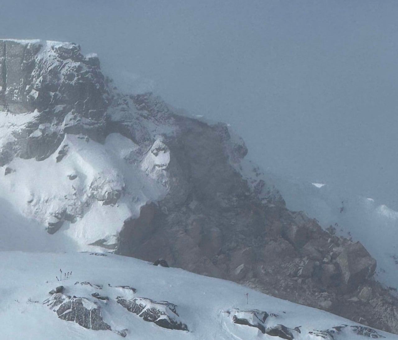 A debris field from a rockfall on a snowy mountain. 