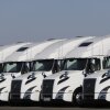 A line of white semi-trucks parked side by side. 