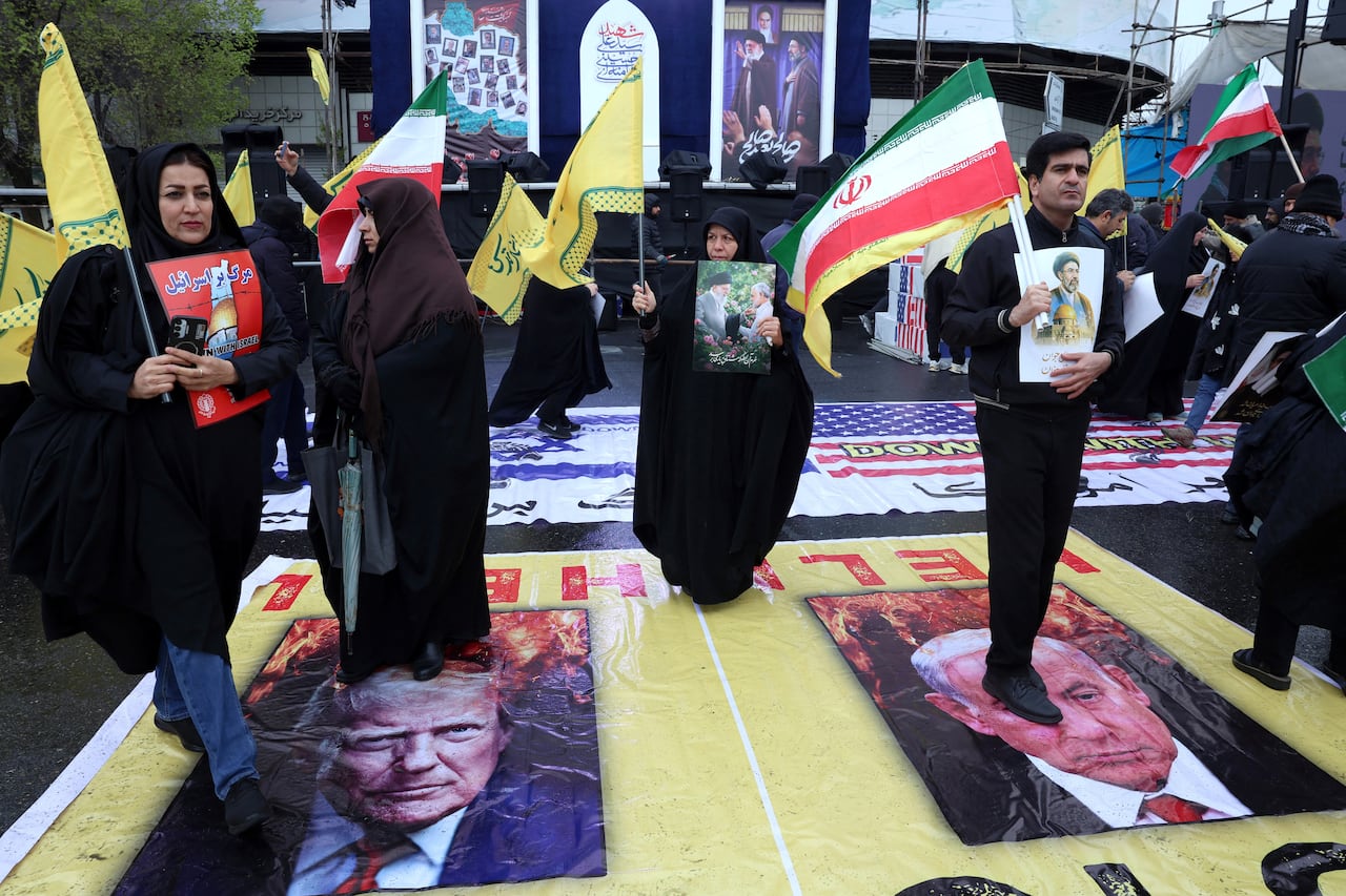 Iranians stand on posters depicting images of the US president Donald Trump (L) and Israeli Prime Minister Benjamin Netanyahu.