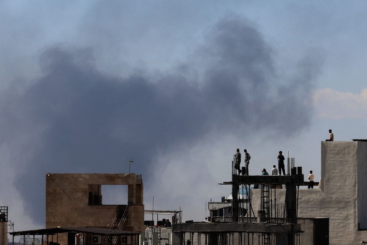 Residents watch from the roofs of their houses as plumes of smoke rise in Tehran on March 1.