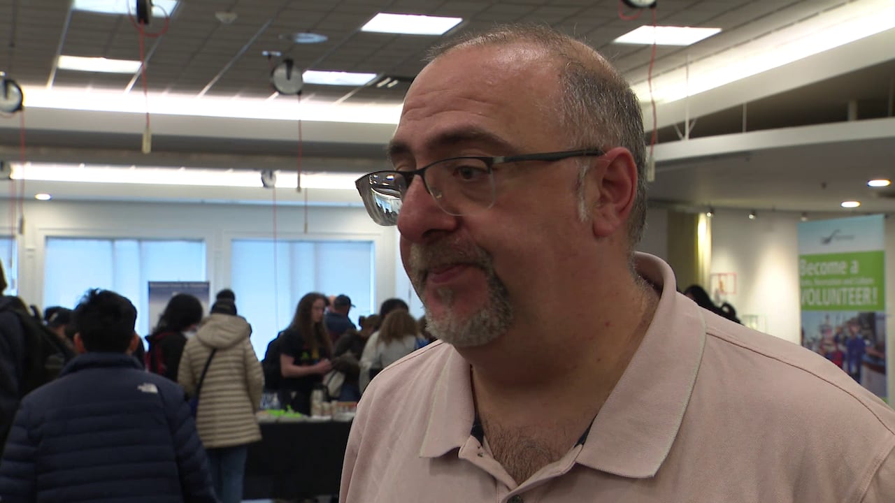 A balding man speaks in a career fair environment.