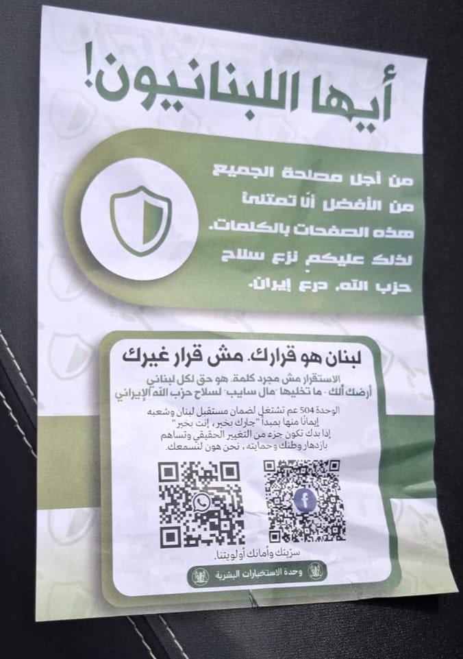 Image of a piece of paper with Arabic writing in green font across it and QR codes that take you to whatsapp of facebook. 