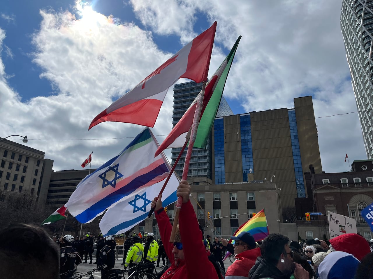 People holding up Israel, Canada, Iran, Pride flags