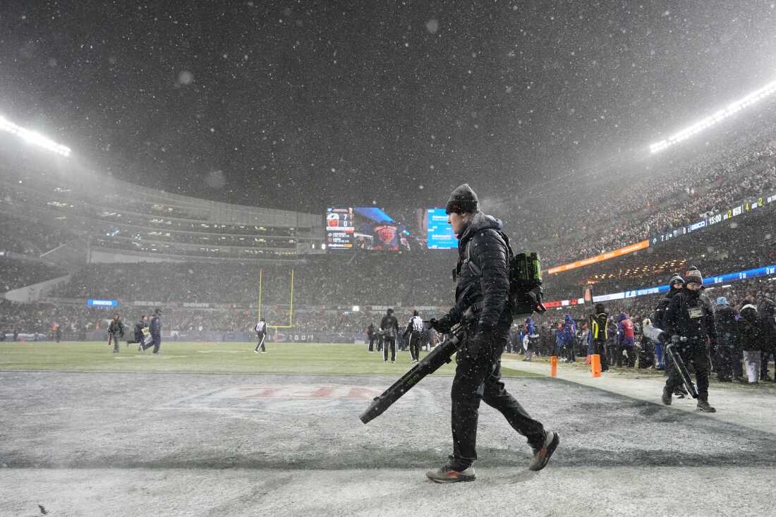 Grounds crew members glow snow off the field at Soldier Field during the first half of an NFL football divisional playoff game between the Chicago Bears and the Los Angeles Rams Sunday, Jan. 18, 2026, in Chicago. 