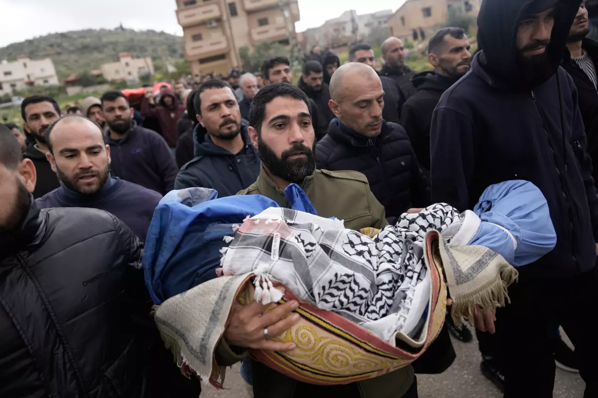 A Palestinian man carries Muhammad Bani Odeh, 5, at the funeral of four members of the Odeh family who were killed in their car by Israeli security forces during an army operation in Tammun, West Bank, Sunday, March 15, 2026.